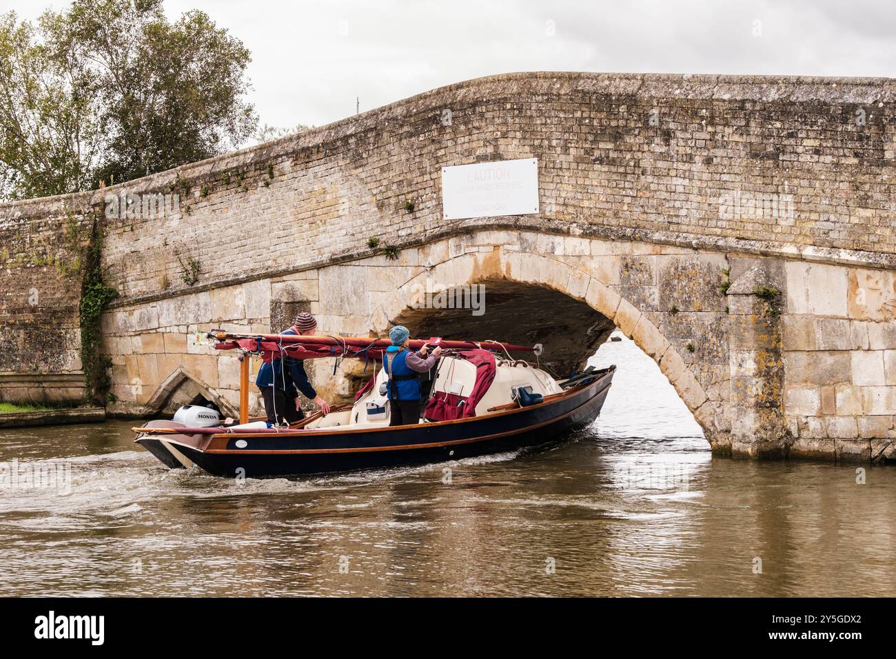 Barca a vela che passa sotto il basso vecchio ponte sul fiume Thurne nel Parco Nazionale di Norfolk Broads. Potter Heigham, Norfolk, East Anglia, Inghilterra, Regno Unito, Foto Stock