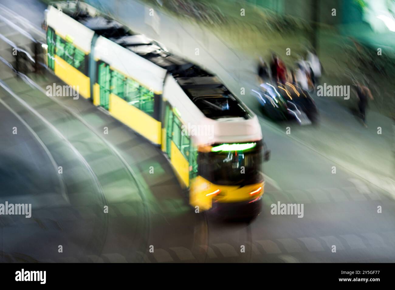 Un tram si muove rapidamente attraverso le strade notturne di Berlino, creando un'atmosfera da sogno e misteriosa. Foto Stock