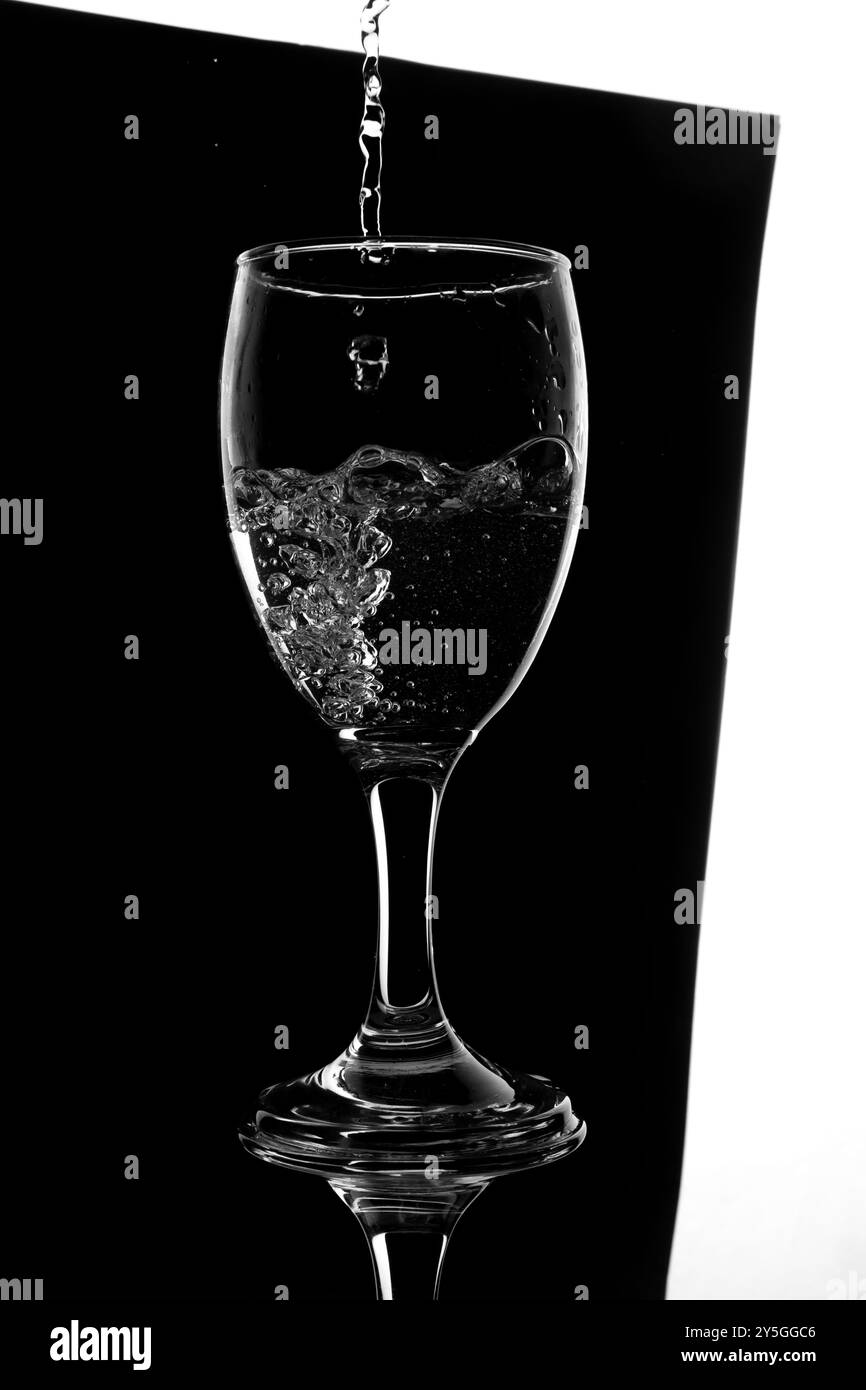 Versare l'acqua svuotare il bicchiere di vino isolato su bianco e nero, spruzzare l'oggetto d'acqua in vetro utilizzando il mockup Foto Stock