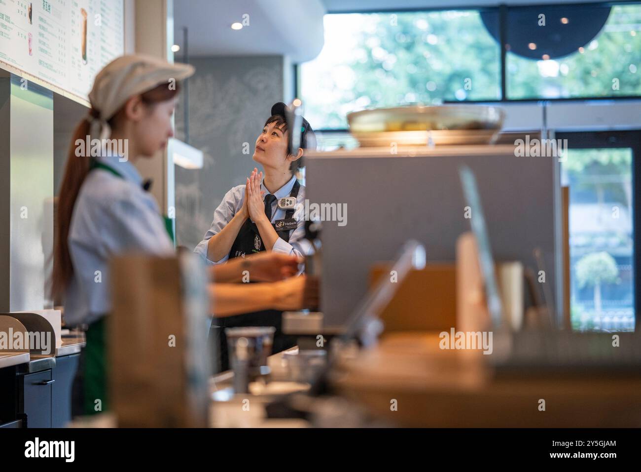 Wuhan, Cina. 22 settembre 2024. Chen Yuanyuan (R) lavora presso uno Starbucks della lingua dei segni a Wuhan, nella provincia cinese di Hubei, 22 settembre 2024. In un caffè nel distretto di Jiang'an, Wuhan, il barista sordo Chen Yuanyuan prepara tazze di caffè piene di amore per i suoi clienti. Cinque anni fa, l'apertura di un linguaggio dei segni Starbucks a Guangzhou, nella provincia del Guangdong della Cina meridionale, ha fatto capire all'appassionato di caffè Chen Yuanyuan, che lavorava in città all'epoca, che essere sorda non era un ostacolo per lei diventare barista. Crediti: Xinhua/Alamy Live News Foto Stock