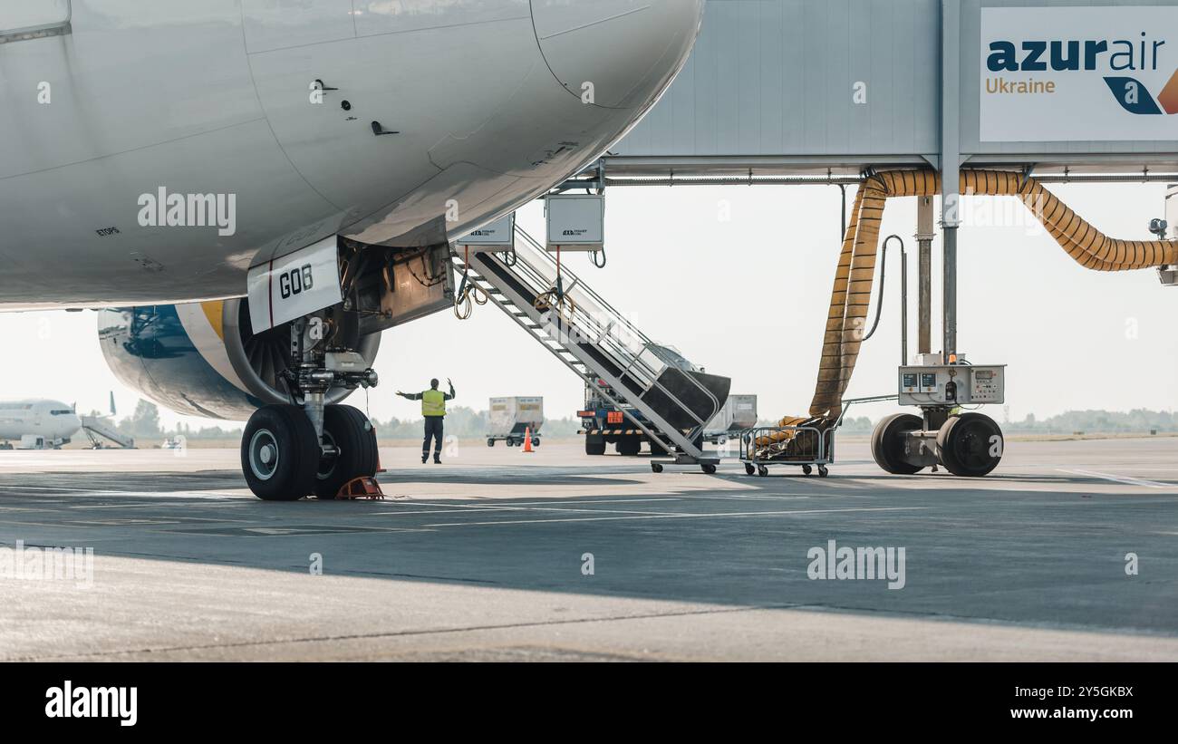 Boeing 777-200 al JET Bridge di mattina. Vista ad angolo basso dell'aereo Ukraine International Airlines (UR-GOB) in preparazione per un volo. Foto Stock