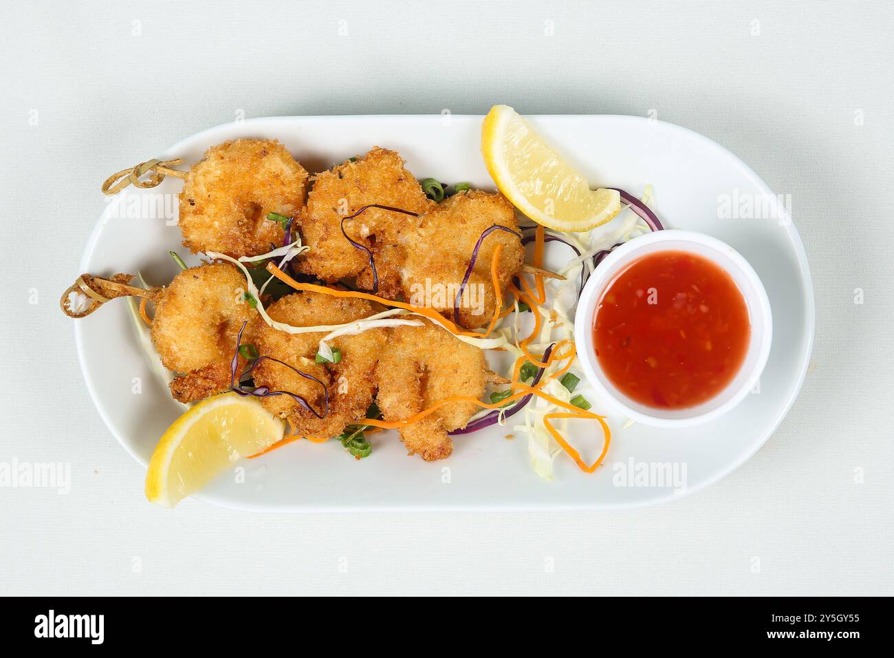 gamberi fritti in profondità su spiedini in un piatto bianco. comodo servizio di spuntini al banchetto. rinfresco per i bambini. vista dall'alto Foto Stock