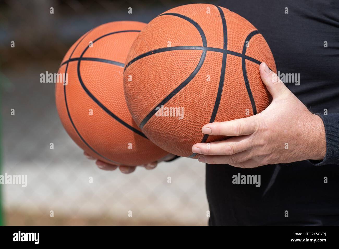 Uomo in abito sportivo nero con due palloni da basket - pronto per l'azione Street Ball. Foto Stock