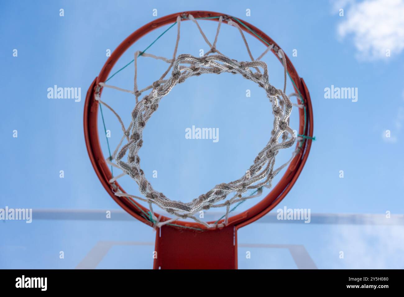 Tabellone in vetro e canestro arancione - angolazione bassa con cielo blu Foto Stock