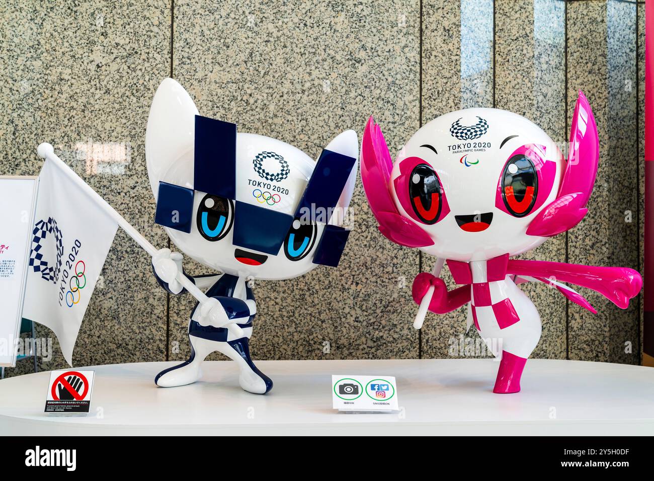 Primo piano di due mascotte Tokyo 2020, una bianca e blu per le Olimpiadi e una rosa e bianca per le paralimpiadi su un piccolo stand bianco. Foto Stock