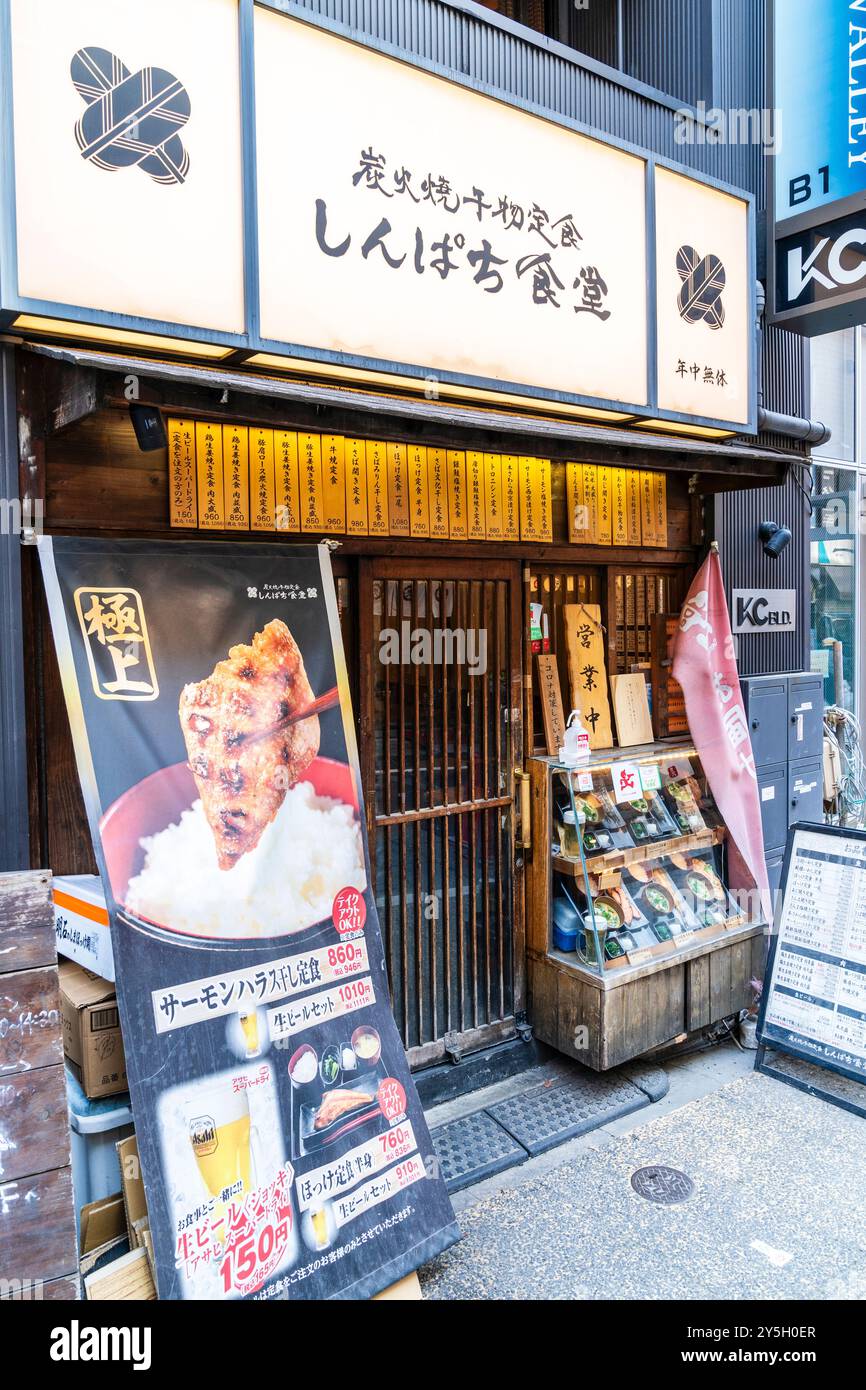 Piccolo ristorante giapponese tradizionale Izakaya con porta scorrevole in legno a lastre e menu' sotto forma di tavolette di legno sopra. Espositore di alimenti in plastica. Foto Stock