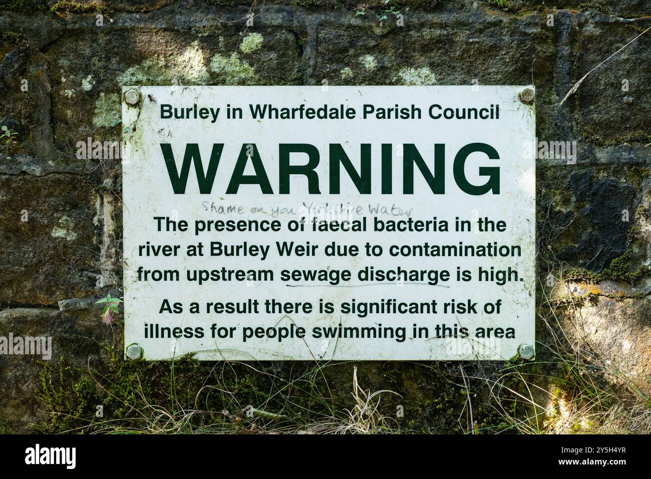 Scarico delle acque reflue nel River Wharfe Warning a Burley, Wharfedale Weir vicino a Ilkley, con graffiti che recitano "vergogna su di te Yorkshire Water" Regno Unito Foto Stock