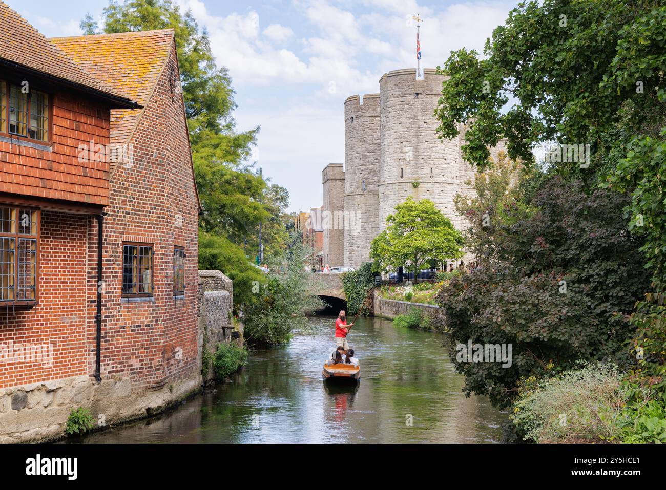 Canterbury, Kent, Regno Unito - settembre 2024: Un uomo che indossa una maglietta rossa punta una barca contenente tre persone lungo il fiume Great Stour a Westgate Gardens. Foto Stock