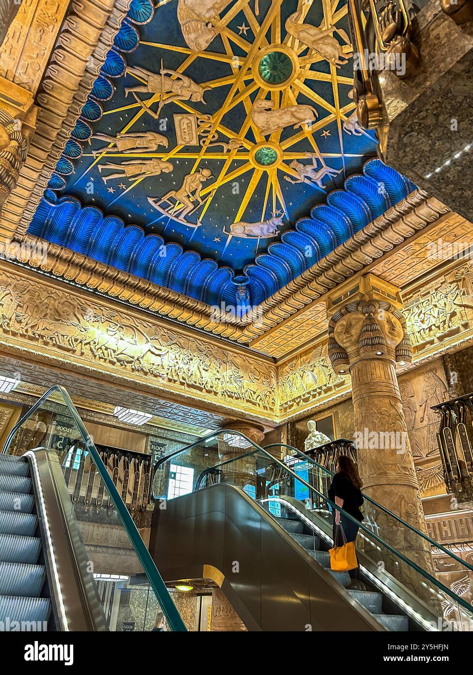 Londra, Gran Bretagna, Low Angle, Inside, Egyptian Style Design, al grande magazzino di Harrods, donna che sale su scala mobile Foto Stock