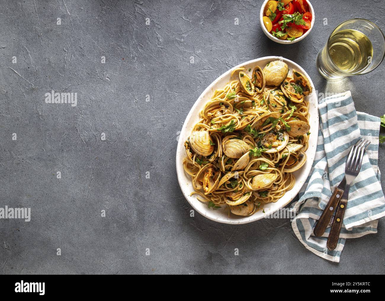 Piatti di pasta. ITALIAN spaghetti alle vongole. Spaghetti vongole sulla piastra bianca con vino bianco e sfondo grigio. Vista superiore Foto Stock