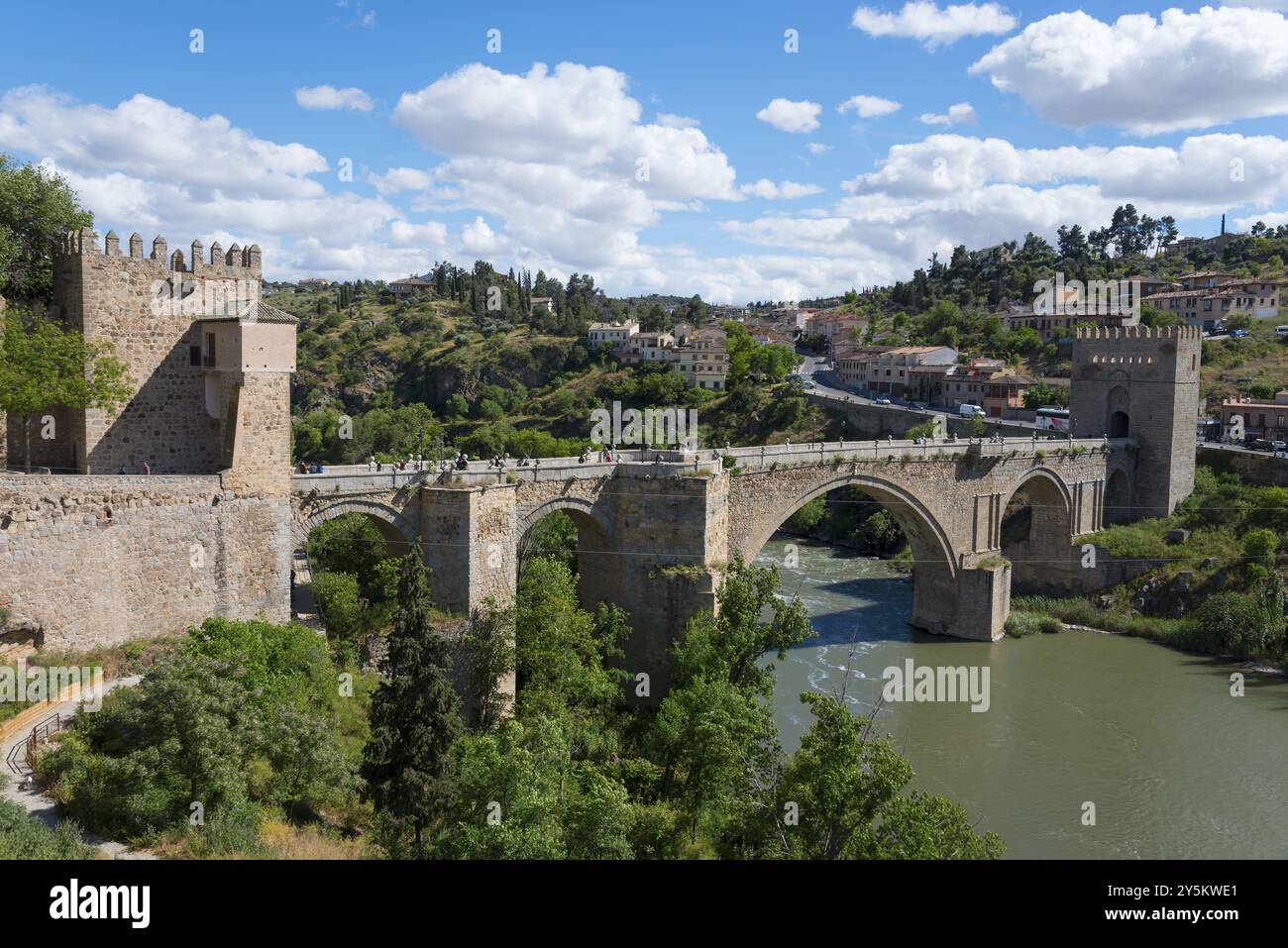 Vecchio ponte sul fiume in pittoresco paesaggio collinare con fortezza e cielo blu con nuvole, Puente de San Martin, Ponte di San Martino, Toledo, Tag Foto Stock