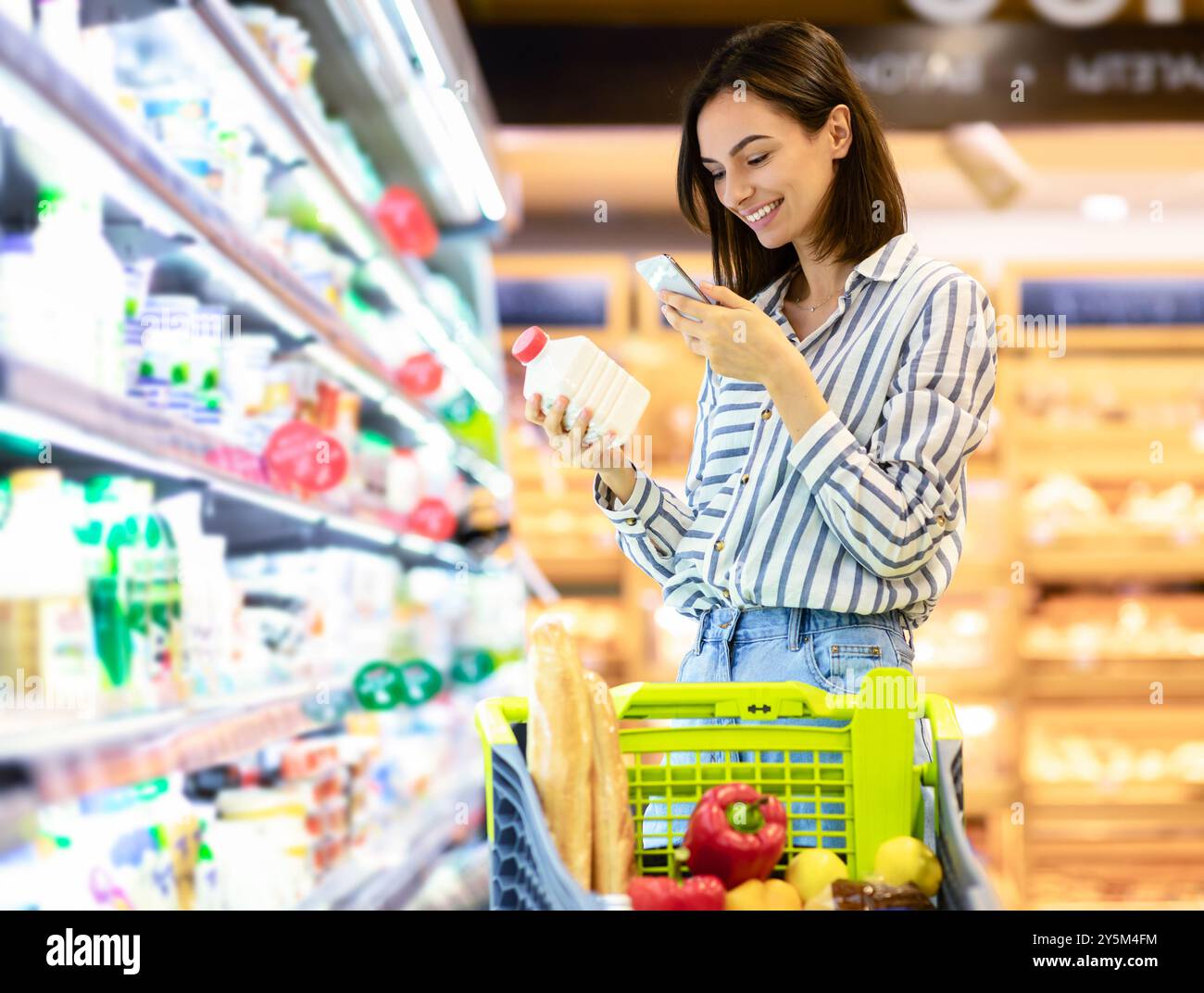 Donna che esegue la scansione del codice sui prodotti utilizzando lo smartphone Foto Stock
