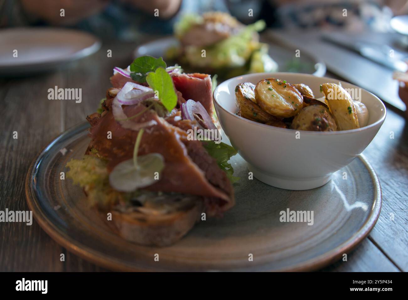 Primo piano di un delizioso piatto nordico con insalata, patate e carne. Tavolo di legno Foto Stock