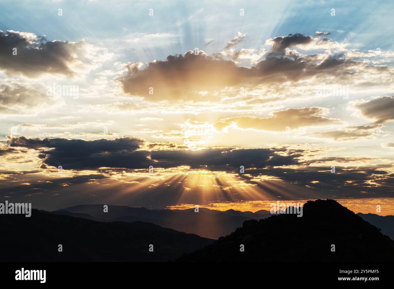 I raggi del sole dell'alba si infrangono attraverso le nuvole sopra le montagne di San Gabriel vicino a Los Angeles, California. Foto Stock