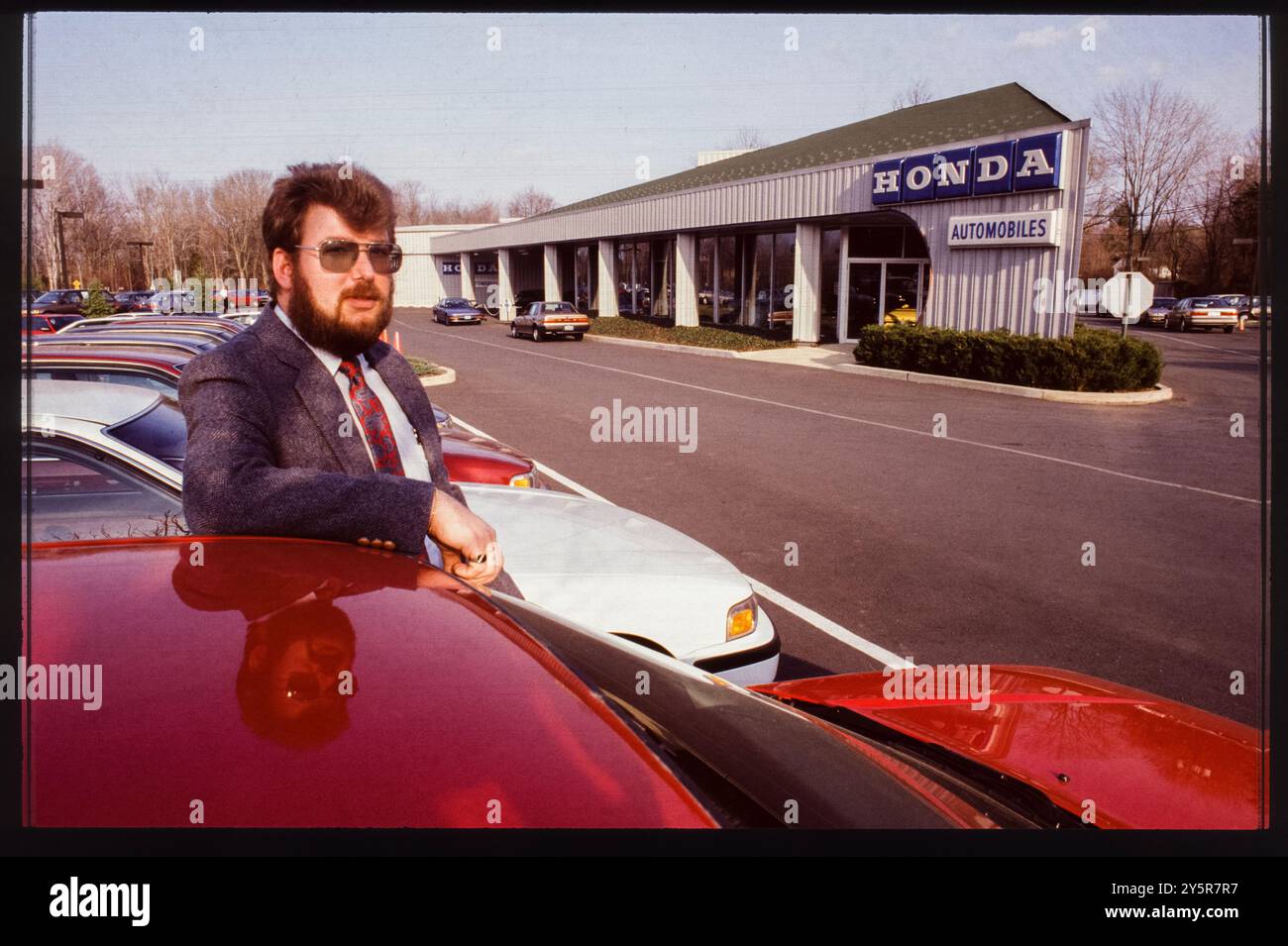 Alla fine degli anni '1980, un venditore posa accanto a una fila di veicoli presso una concessionaria Honda a Trenton, New Jersey Il lotto è pieno di popolari modelli Honda, che riflettono la crescente reputazione del marchio in termini di affidabilità ed efficienza nel mercato statunitense. Foto Stock