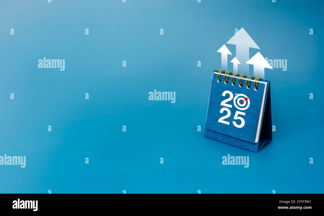 Felice anno nuovo 2025 background. Frecce bianche in alto sulla copertina del calendario da scrivania 2025 in piedi su sfondo blu con spazio per le copie, minimalista. Azienda p Foto Stock