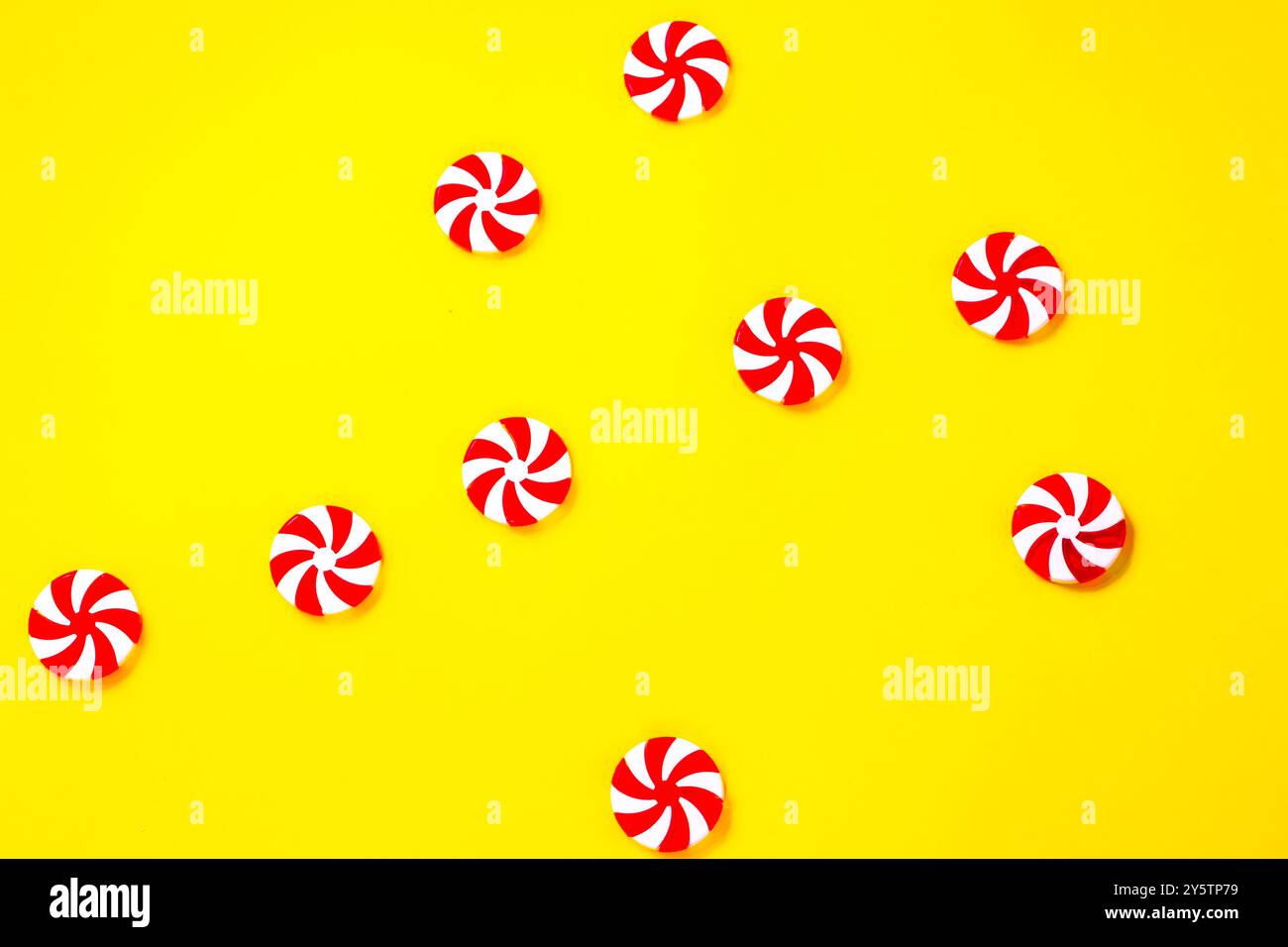 Caramelle natalizie bianche e rosse sparse su sfondo giallo, concetto di cibo dolce durante il periodo natalizio Foto Stock