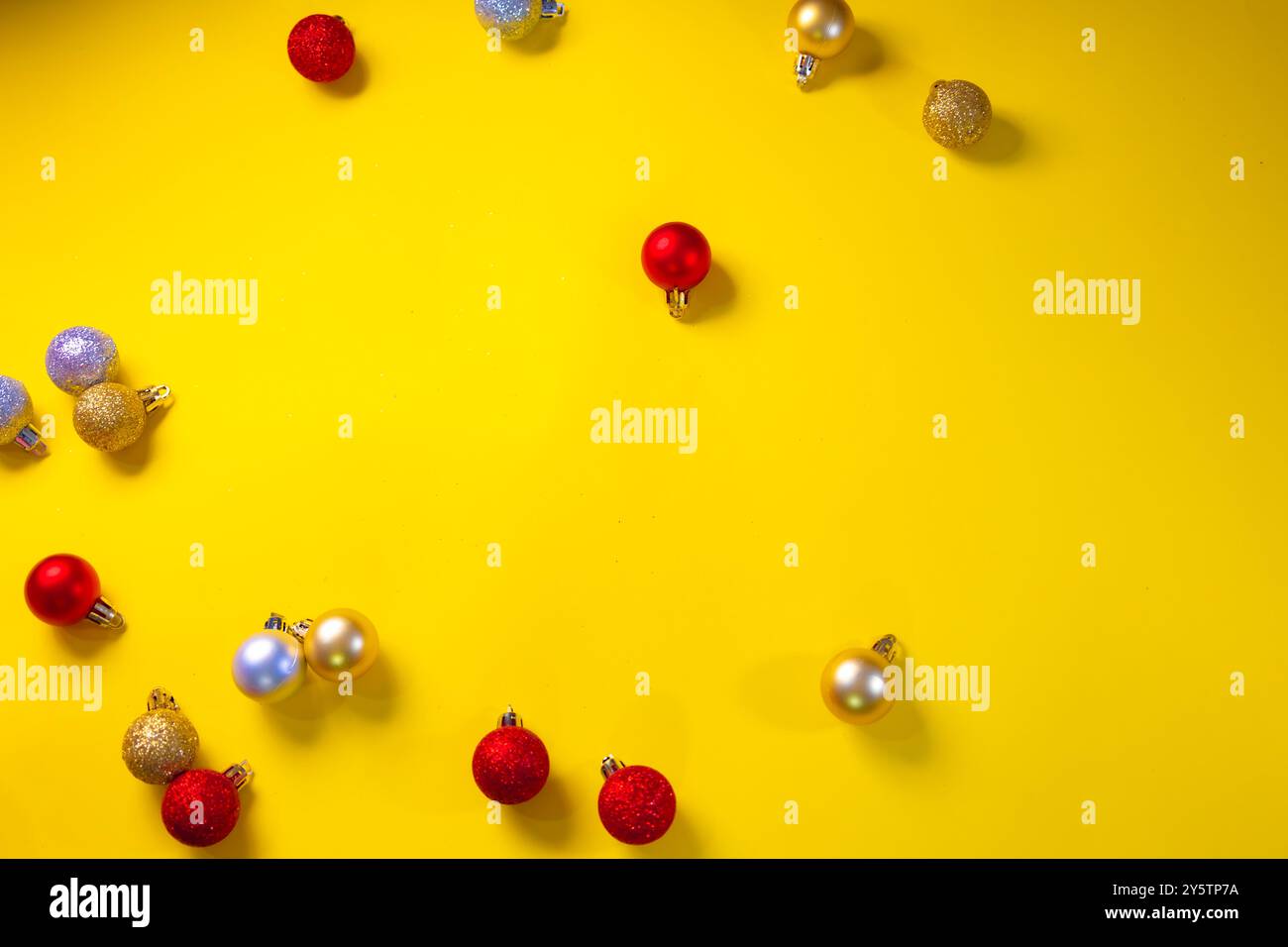 Concetto di palline natalizie rosse, dorate e argentate sparse su sfondo giallo Foto Stock