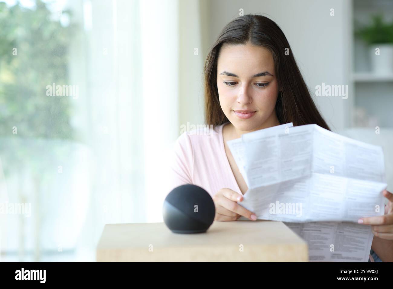 Donna seria che legge il manuale di istruzioni dell'altoparlante intelligente a casa Foto Stock