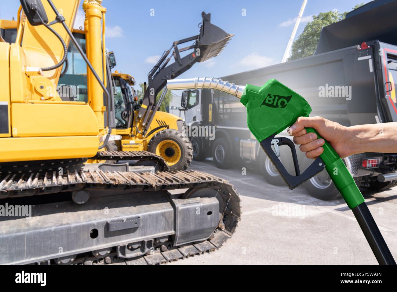 Uomo con ugello per biocarburante su un background di macchine edili. Foto Stock