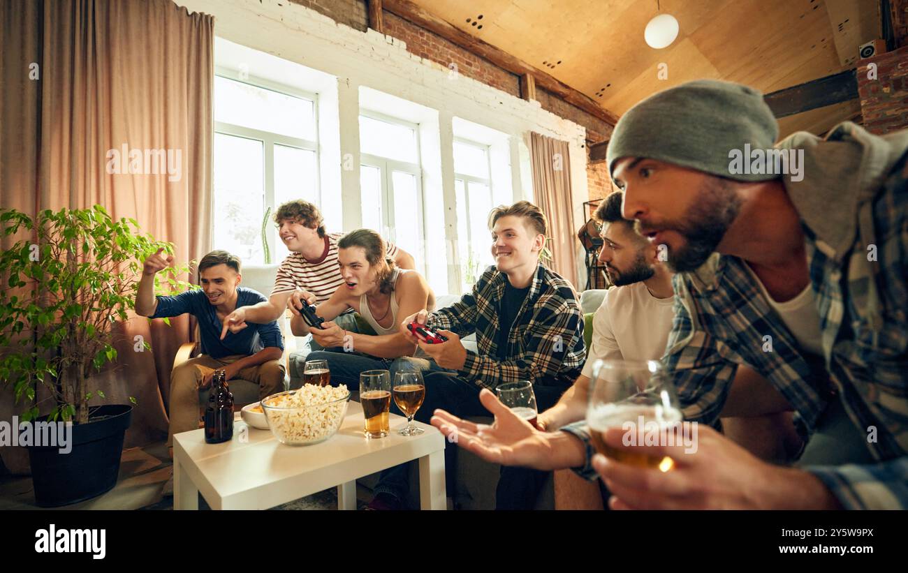 I momenti di vittoria e le grida giocose avvicinano il gruppo di amici, godendosi il loro tempo insieme con un drink e un'azione di gioco intensa. Foto Stock