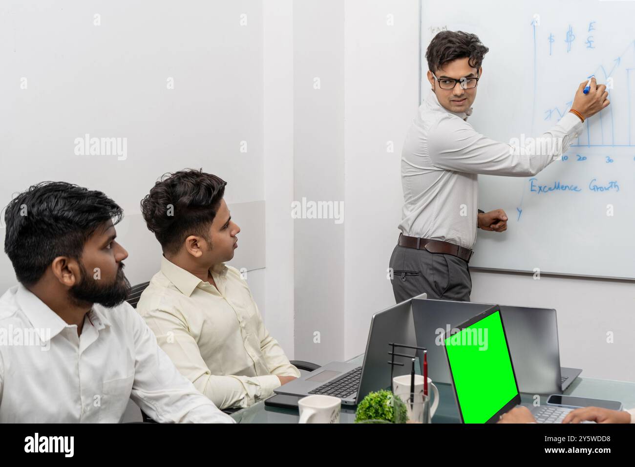 Questa accattivante foto di scorta cattura un professionista indiano che partecipa attivamente a una sessione di formazione all'interno di un ufficio moderno. L'immagine sh Foto Stock