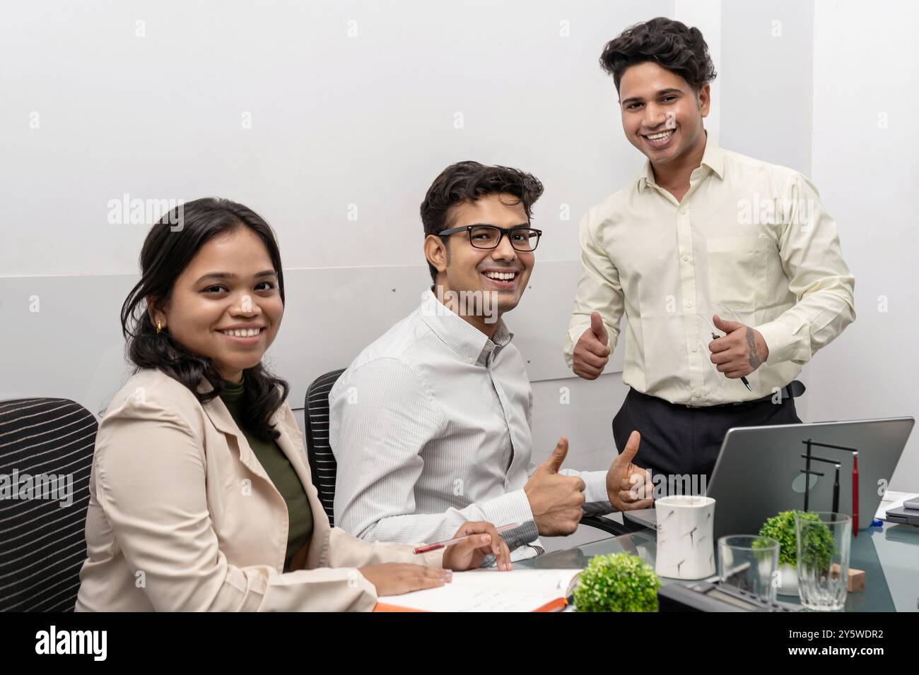 Un team aziendale diversificato e multirazziale di varie età celebra il successo di carriera in un ambiente di ufficio moderno. Il team è visibilmente entusiasta, mostrando il suo valore Foto Stock