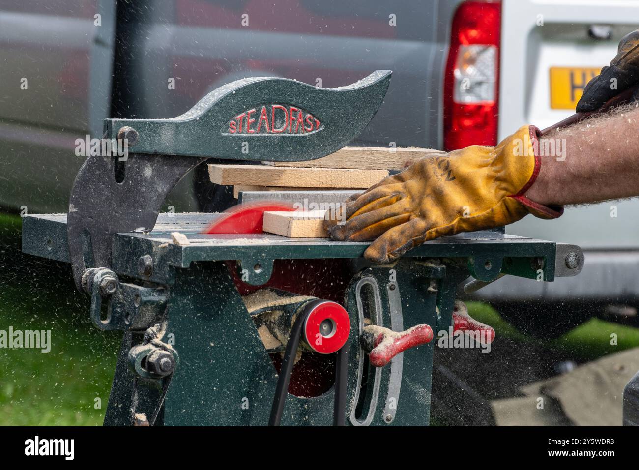 Uomo che utilizza una sega circolare a vapore per tagliare piccoli pezzi di legno al Newbury Show 2024, Berkshire, Inghilterra, Regno Unito Foto Stock