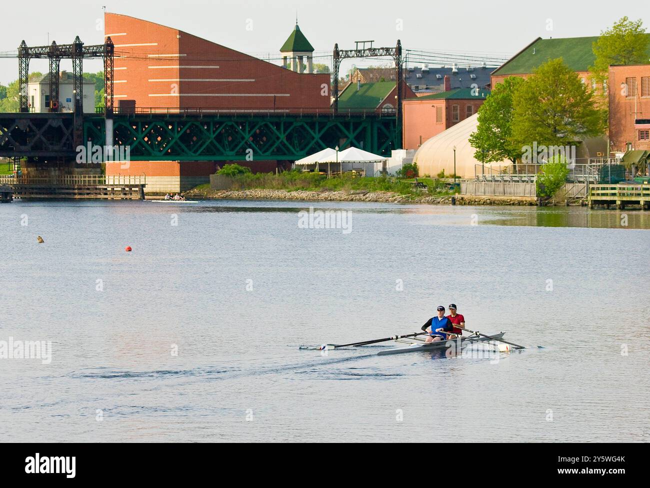 Due rematori guidano il loro scull lungo il fiume. Foto Stock