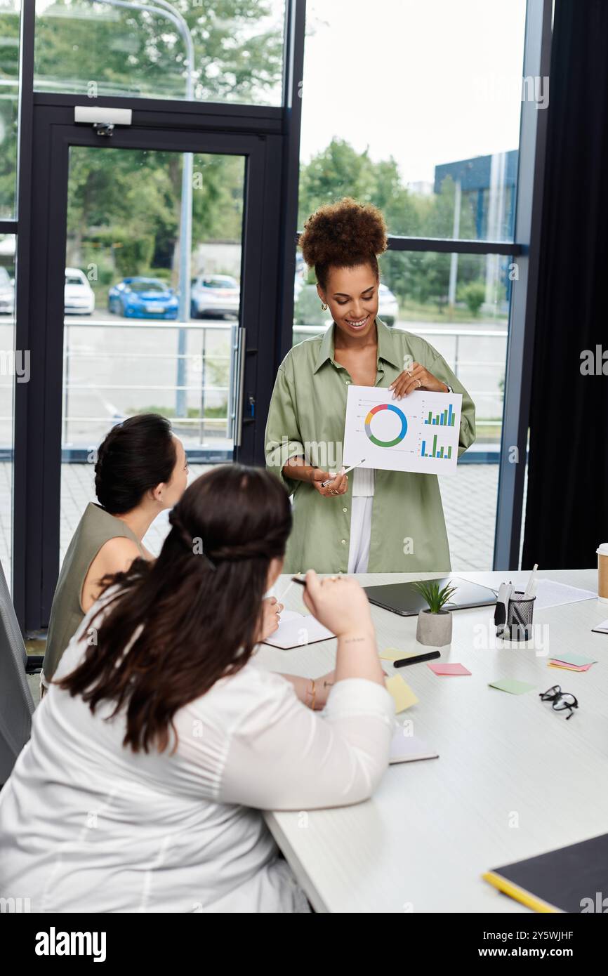 Una donna d'affari sicura conduce una discussione con i colleghi, mostrando le sue capacità di presentazione. Foto Stock