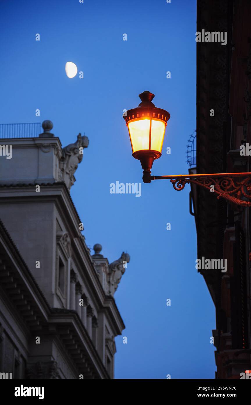 L'elegante lampada da strada illumina una strada romana sotto un cielo illuminato dalla luna Foto Stock