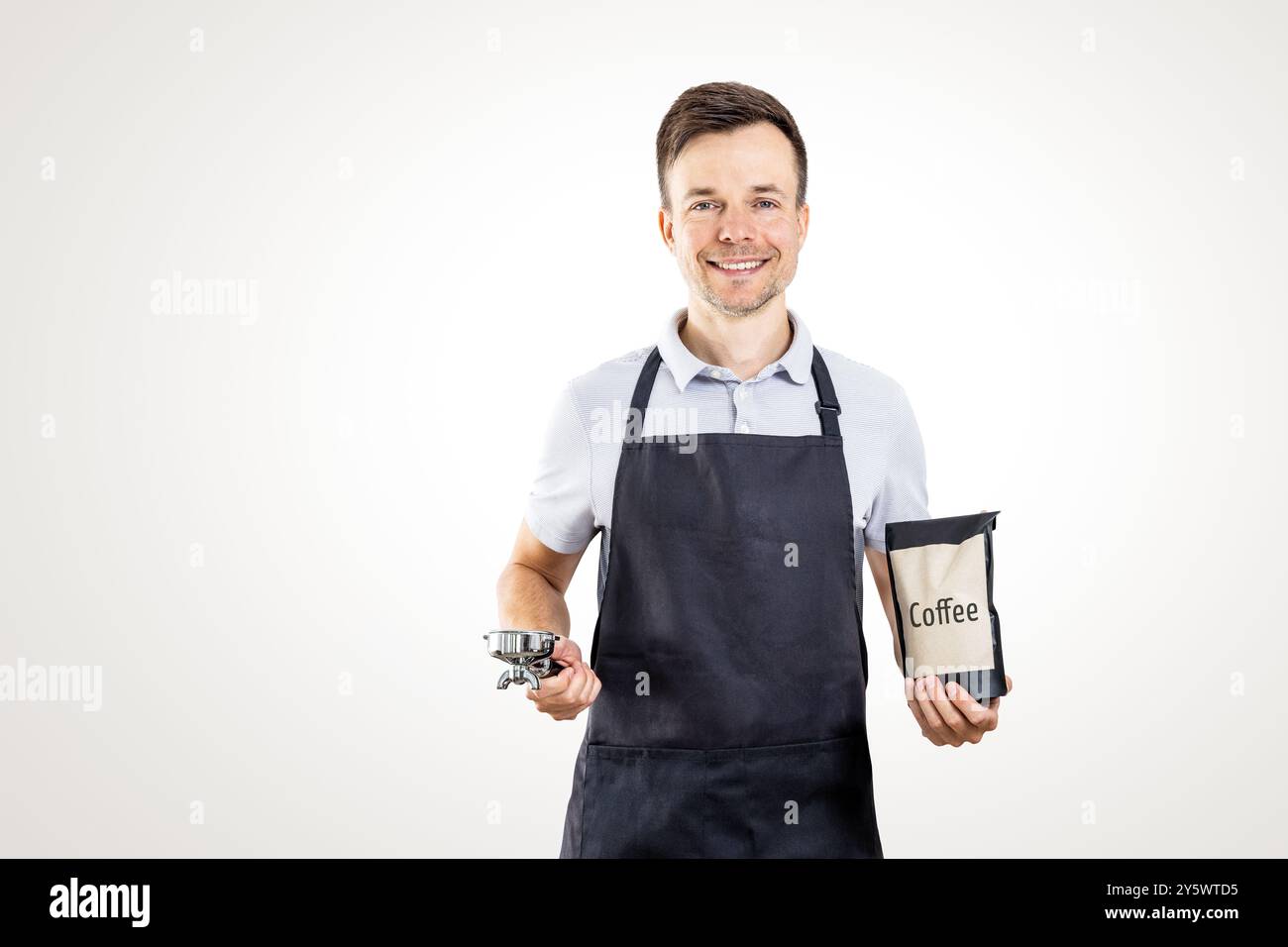 Barista sorridente con portafiltro e sacchetto per caffè Foto Stock