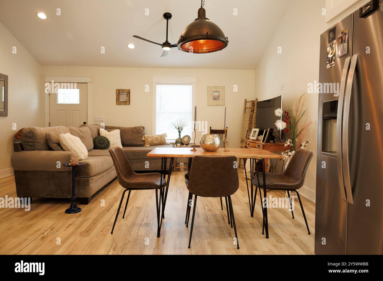 Cucina moderna e zona pranzo con pavimenti in legno, tavolo da pranzo per quattro, frigorifero in acciaio inox e un comodo divano, Florida, USA Foto Stock