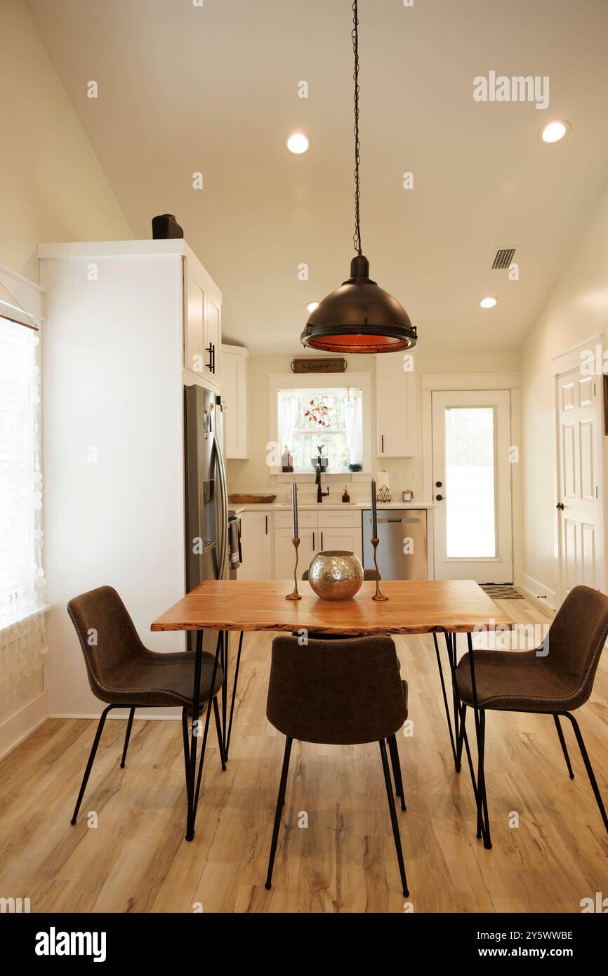 Moderna sala da pranzo con tavolo in legno, sedie marroni e grande lampada a sospensione, Florida, USA Foto Stock