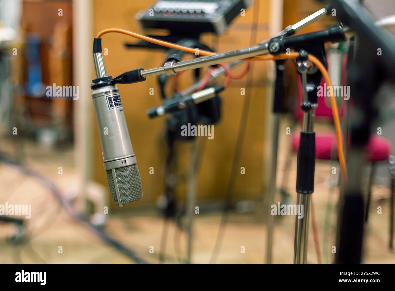 Microfono da studio con filtro pop su sfondo sfocato di apparecchiature musicali. Foto Stock