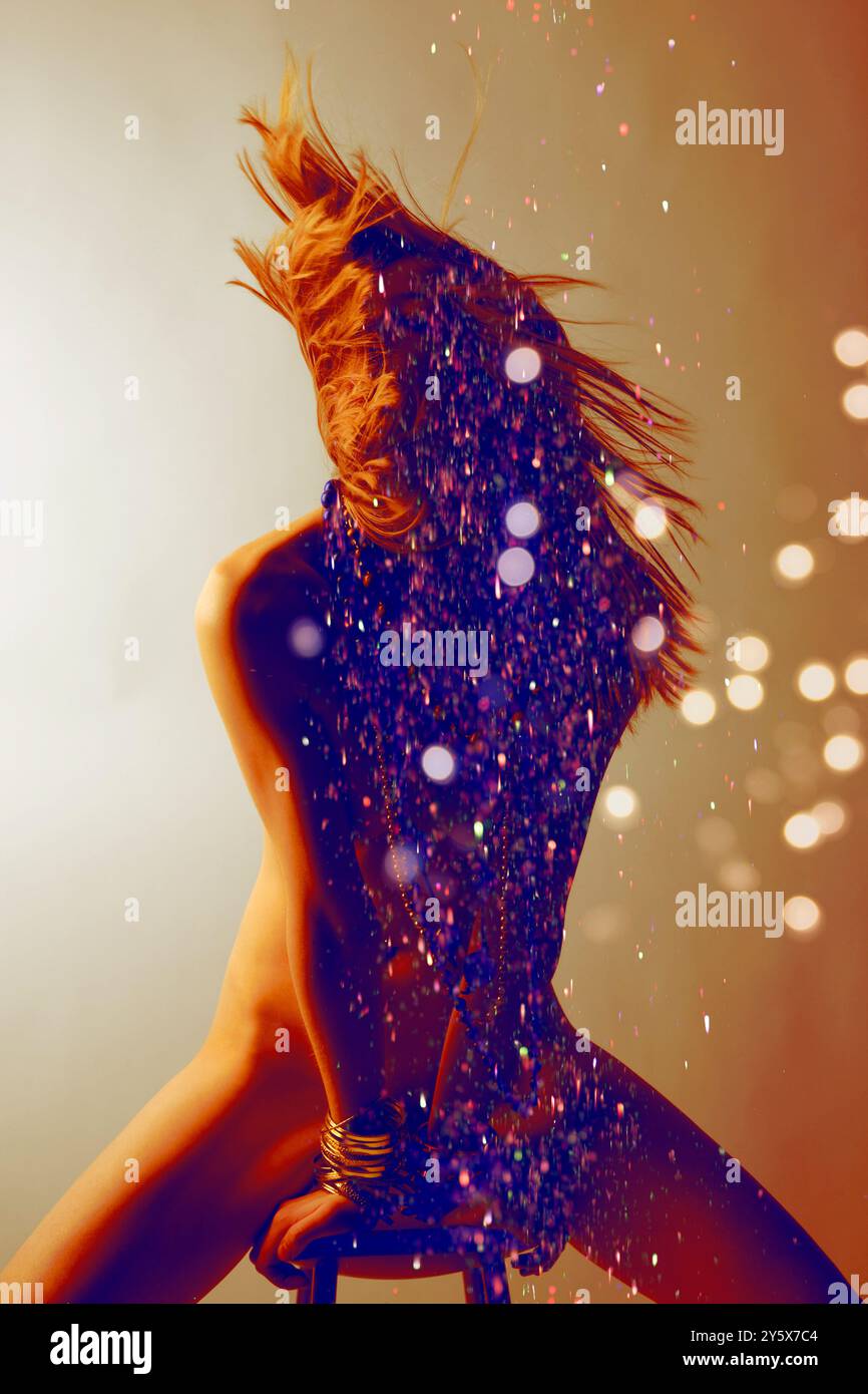Donna con silhouette dal movimento dinamico dei capelli circondata da scintillanti scintillanti e calde luci. Foto Stock