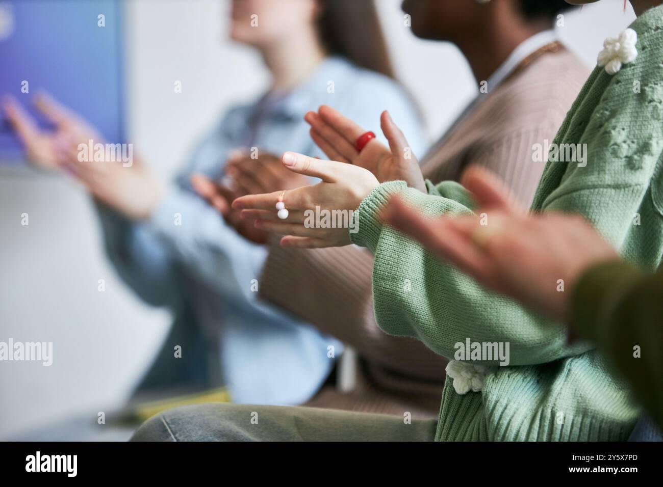 Gruppo di persone che battono le mani durante la sessione interattiva del workshop visibile in primo piano, si concentrano sulle mani con persone diverse in background Foto Stock
