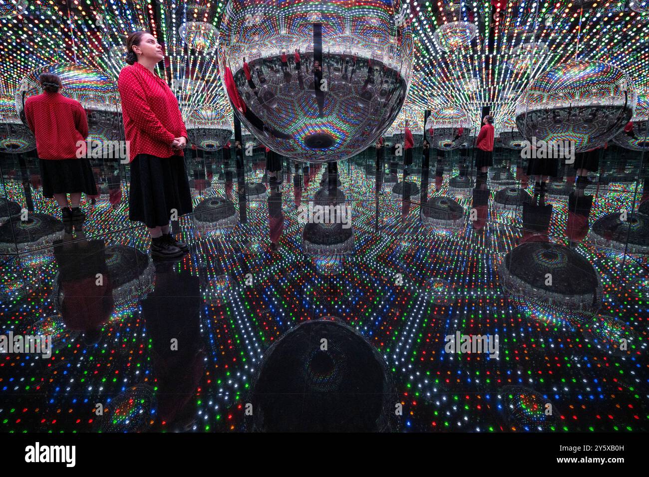 Londra, Regno Unito. 23 settembre 2024. Un membro dello staff in anteprima di Every Day i Pray for Love, la quattordicesima mostra personale di Yayoi Kusama con la galleria Victoria Miro che presenta l'ultima serie di dipinti e sculture dell'artista e una nuova stanza a specchio dell'Infinito intitolata "Beauty described by a Spherical Heart", 2024, (nella foto). La mostra si svolge presso la galleria Wharf Road di Victoria Miro dal 25 settembre al 2 novembre 2024. Crediti: Stephen Chung / Alamy Live News Foto Stock