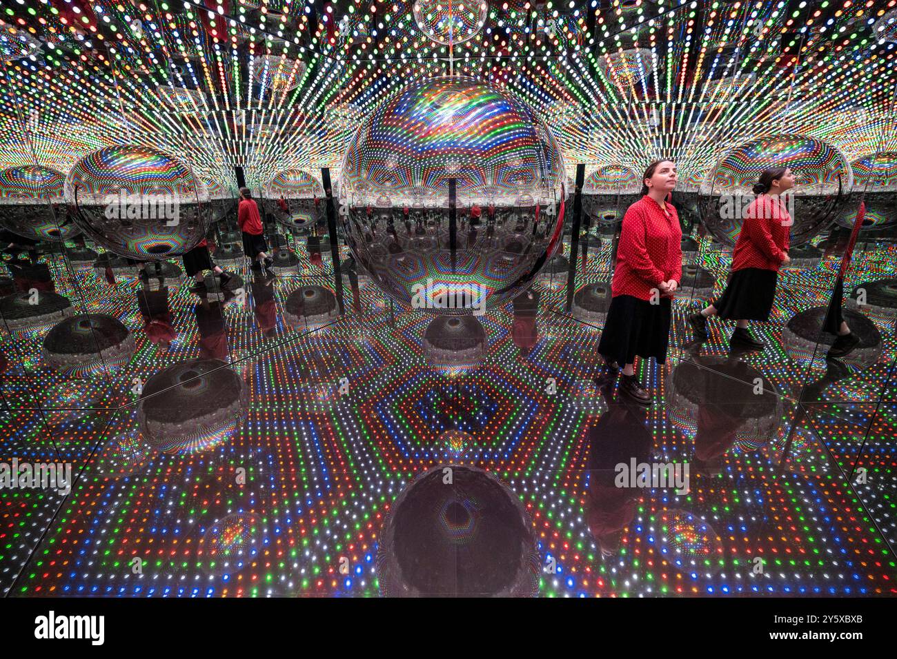 Londra, Regno Unito. 23 settembre 2024. Un membro dello staff in anteprima di Every Day i Pray for Love, la quattordicesima mostra personale di Yayoi Kusama con la galleria Victoria Miro che presenta l'ultima serie di dipinti e sculture dell'artista e una nuova stanza a specchio dell'Infinito intitolata "Beauty described by a Spherical Heart", 2024, (nella foto). La mostra si svolge presso la galleria Wharf Road di Victoria Miro dal 25 settembre al 2 novembre 2024. Crediti: Stephen Chung / Alamy Live News Foto Stock