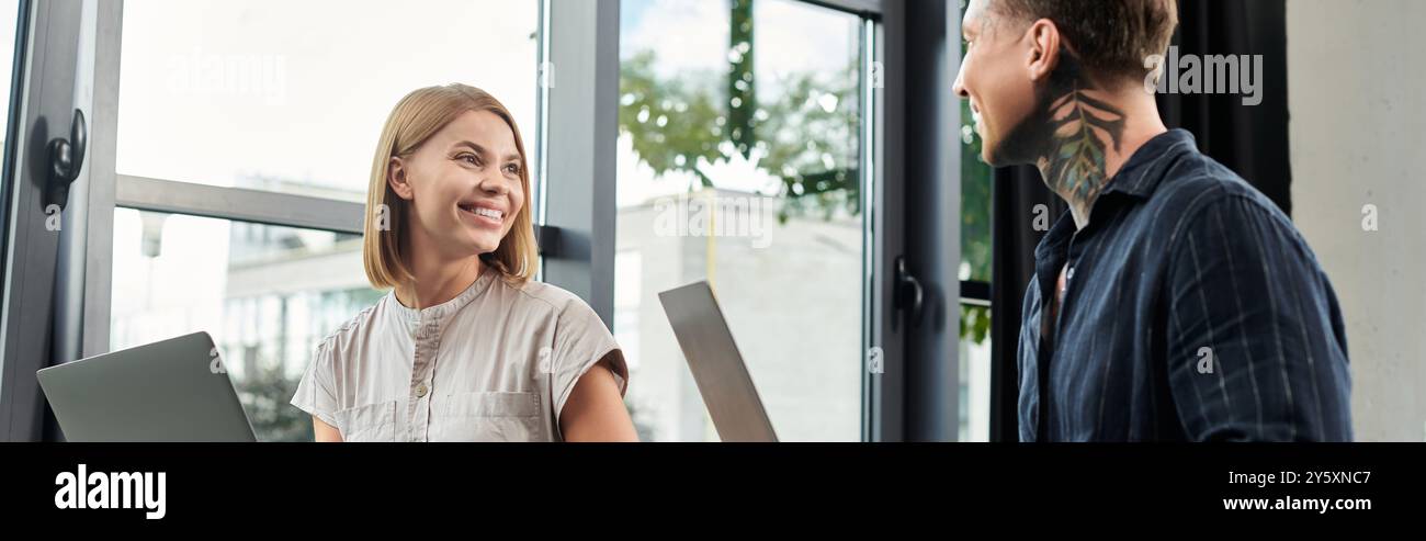 Due giovani colleghi condividono idee e sorrisi in un ambiente di ufficio moderno. Foto Stock