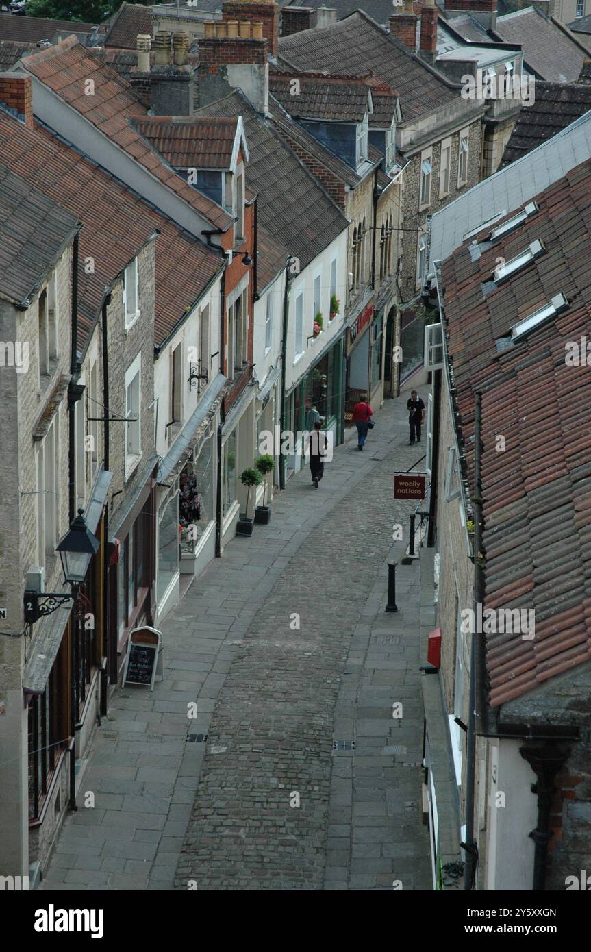 Vista dall'alto verso il basso sui ripidi tetti piastrellati delle case e dei negozi sulla collina di Catherine acciottolata a Frome Somerset in una tranquilla giornata estiva Foto Stock