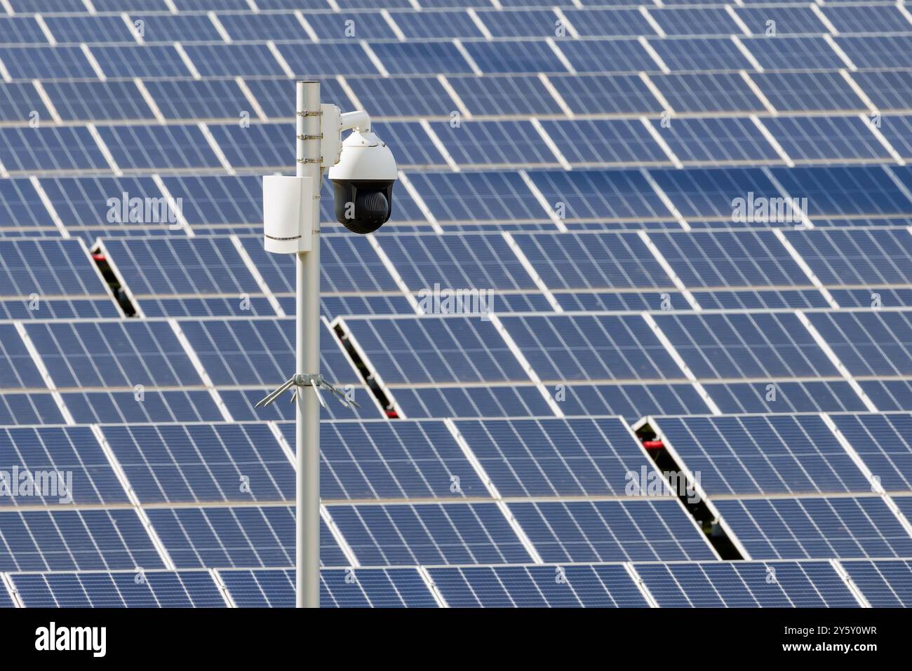 Telecamera di sorveglianza di fronte a un grande campo industriale di pannelli solari Foto Stock