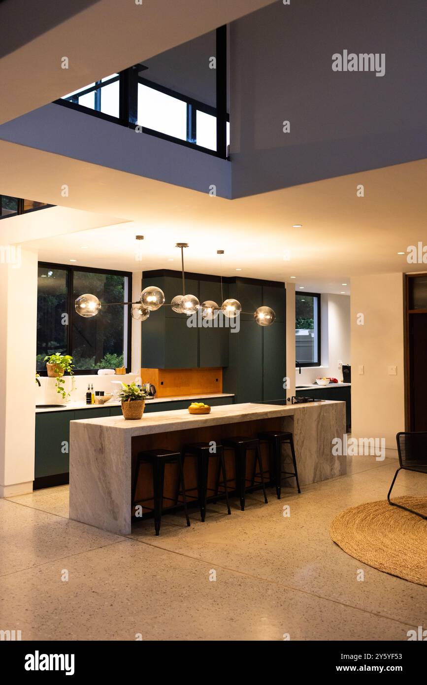 Cucina moderna con isola in marmo, sgabelli da bar, eleganti luci a sospensione e spazio per copie Foto Stock