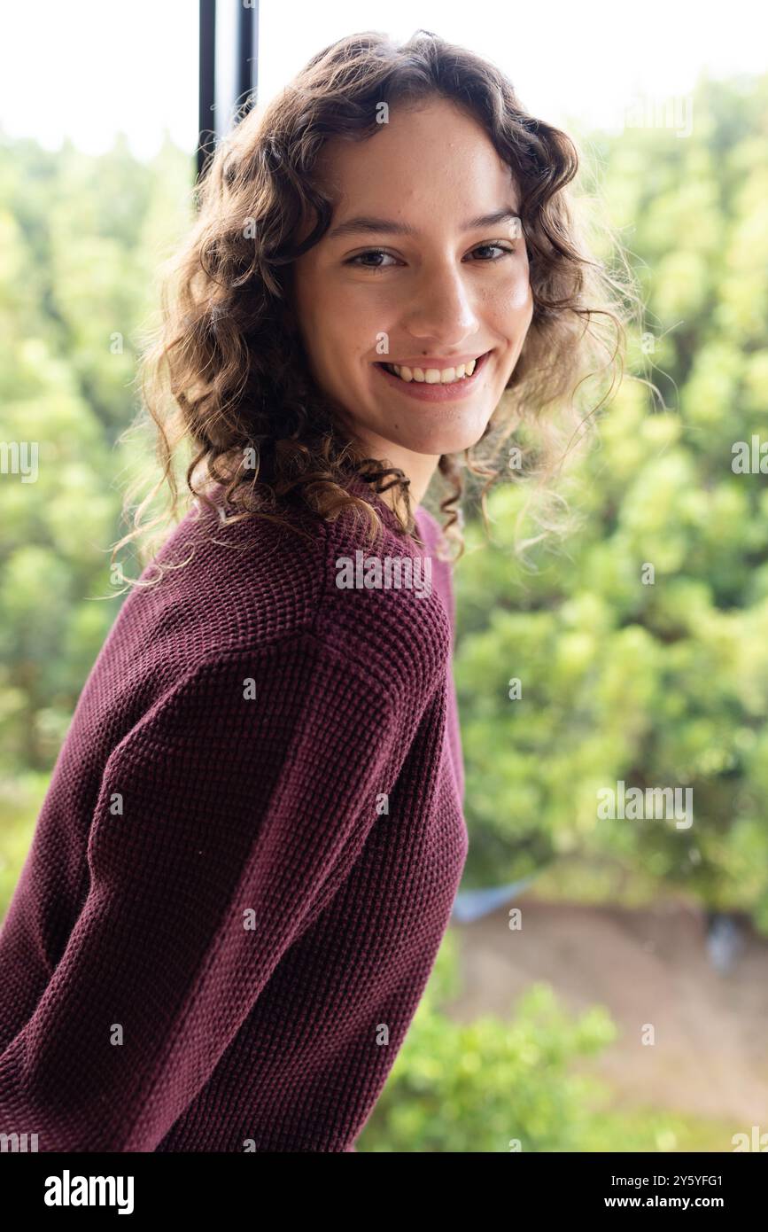 Donna sorridente in un comodo maglione che si diverte a casa Foto Stock