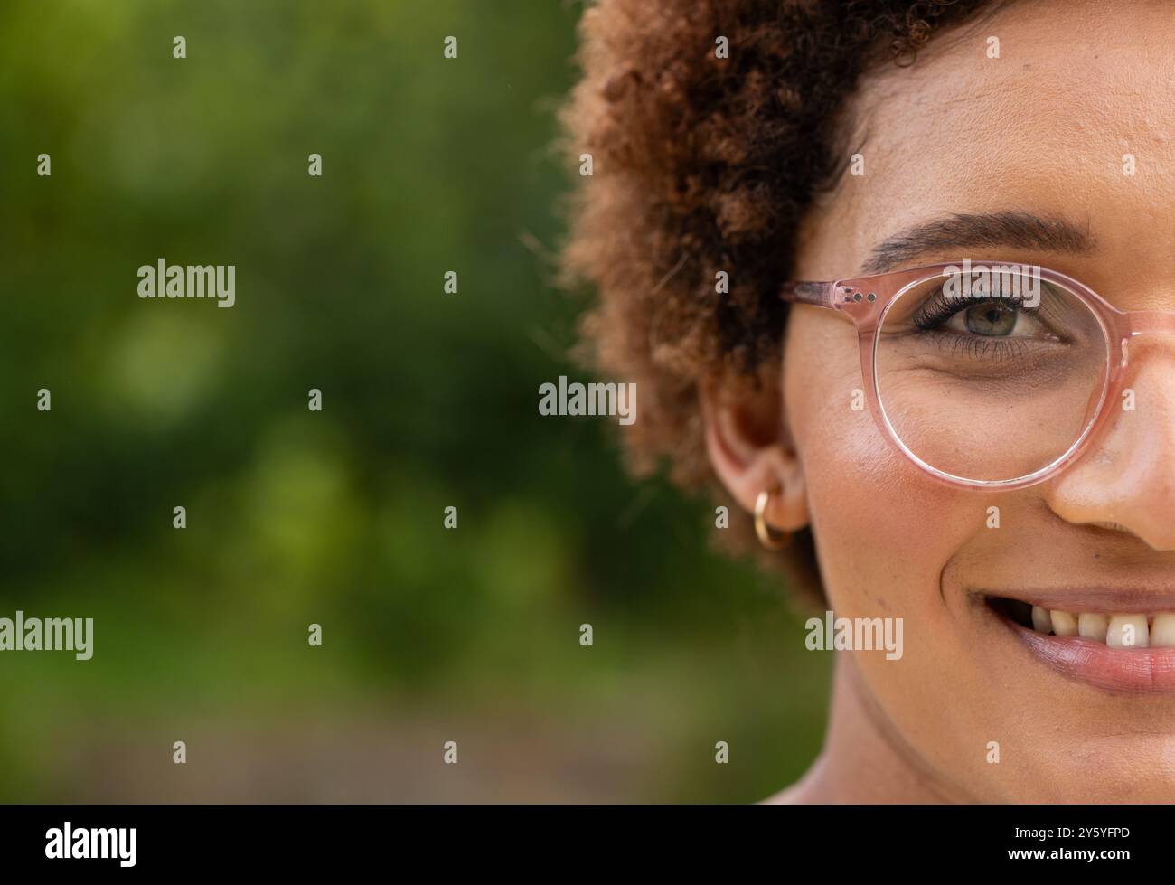 Donna sorridente con occhiali che si gode una scena all'aperto Foto Stock