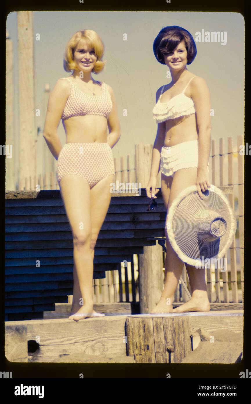 Due donne in bikini posano su una terrazza soleggiata sulla spiaggia, mostrando le tendenze della moda estiva nella California meridionale. Foto Stock