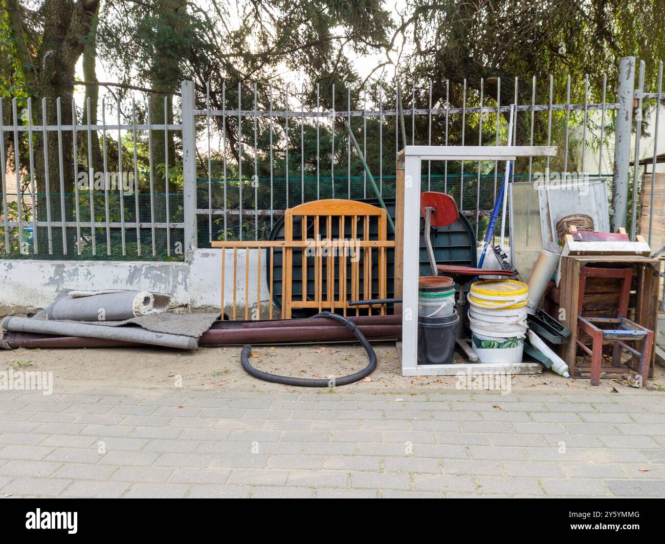 Vari oggetti scartati e mobili vicino a una recinzione stradale Foto Stock