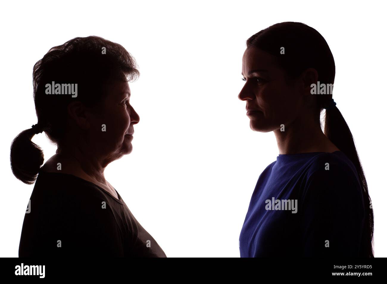 Silhouette scura di una donna anziana, una pensionata di fronte a una giovane donna, una madre e una figlia - isolata, sfondo bianco Foto Stock
