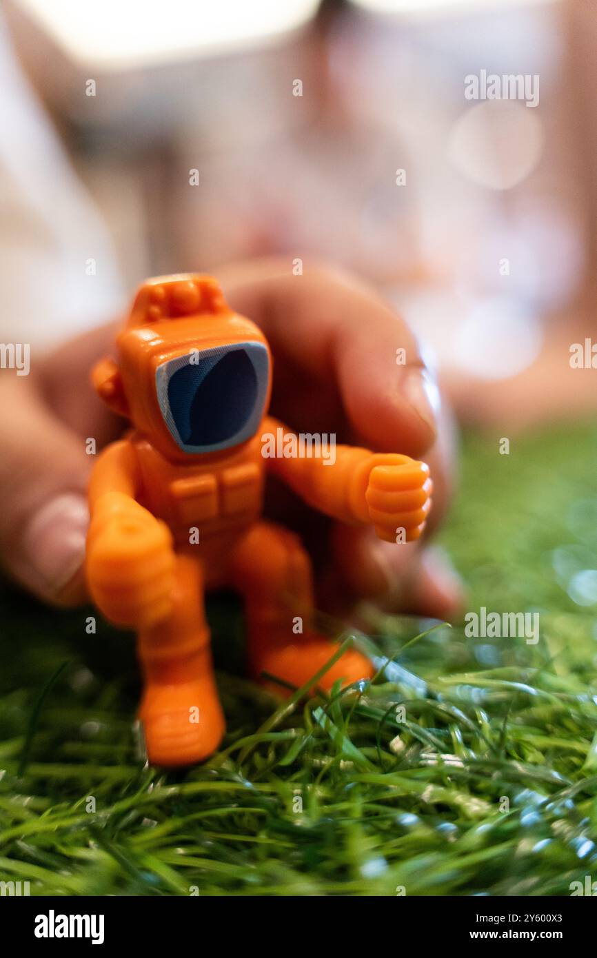 scimmia robot giocattolo arancione su erba verde bambino che afferra a mano Foto Stock