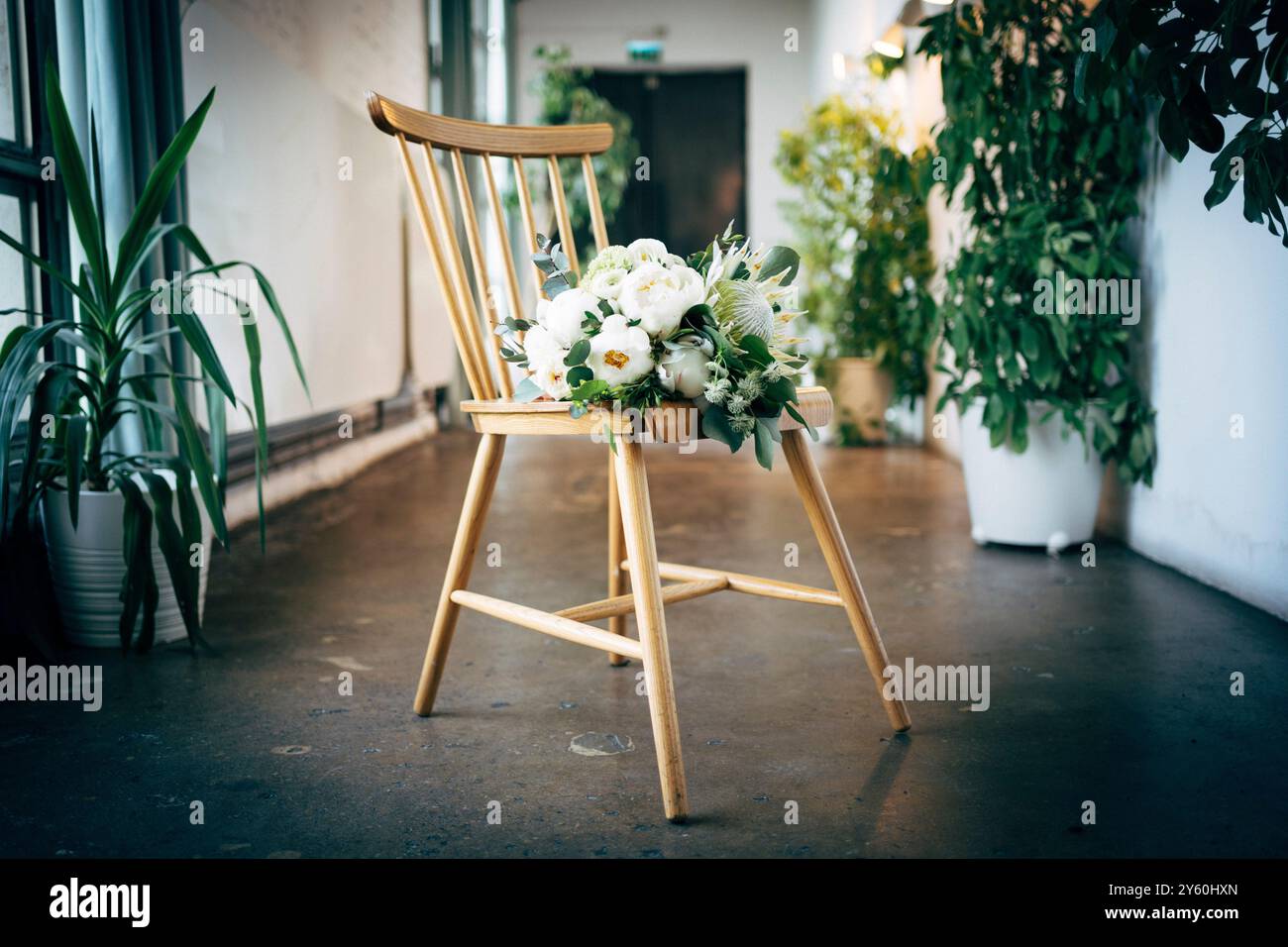 Elegante bouquet floreale su sedia in legno in un ambiente interno minimalista Foto Stock